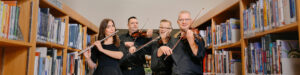 Orkesterin huilisti ja 3 viulistia soittavat kirjastossa.